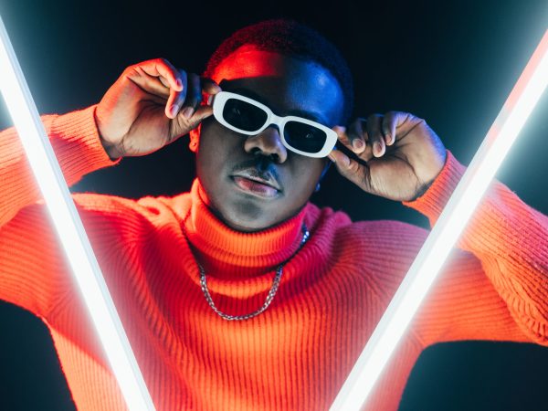 Night portrait. Fashionable man. Cyberpunk trend. Futuristic stylish confident guy in sunglasses LED lamp neon light on dark background.